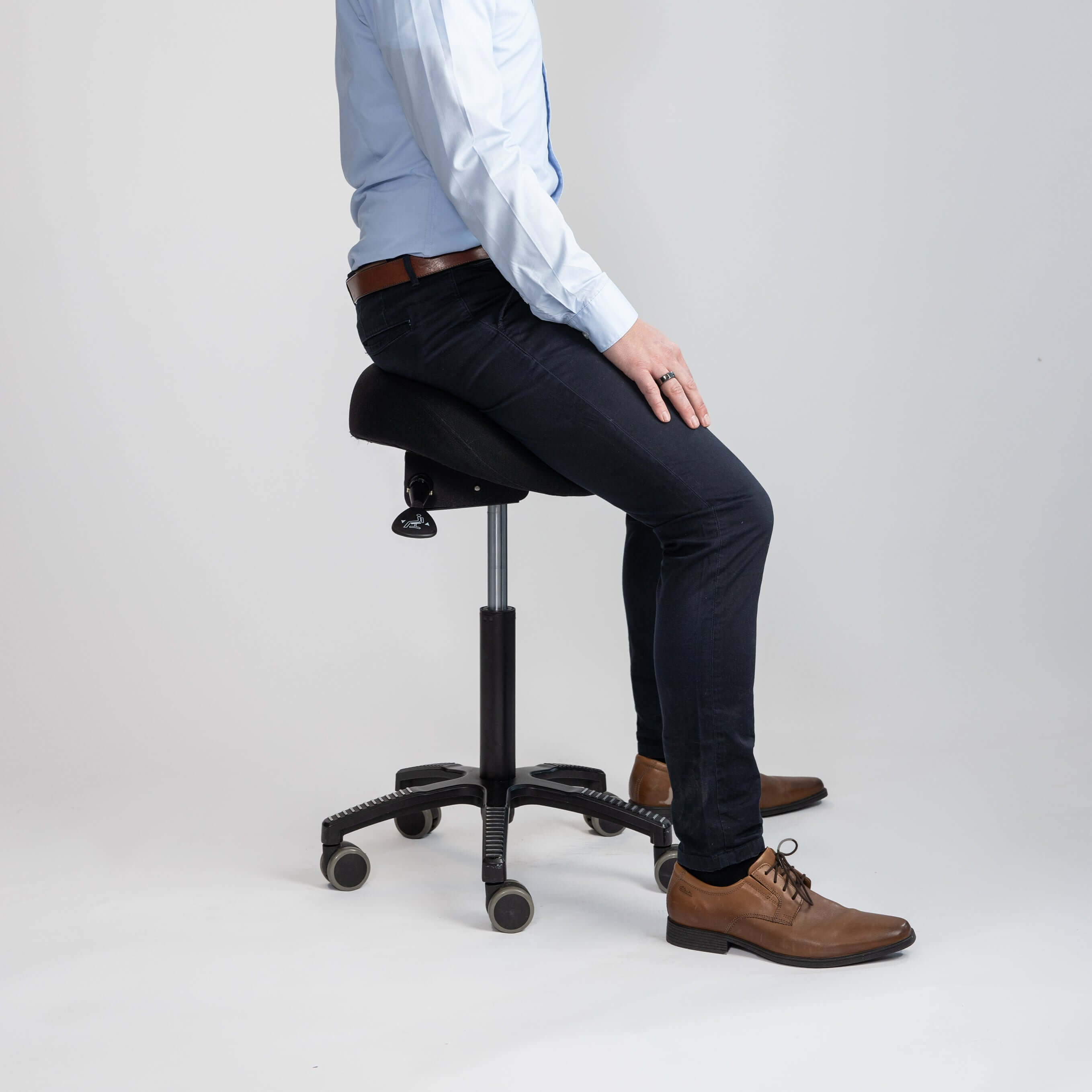 Ergonomic black fabric soft saddle chair with adjustable tilt for comfort and support in office settings, shown with user sitting.