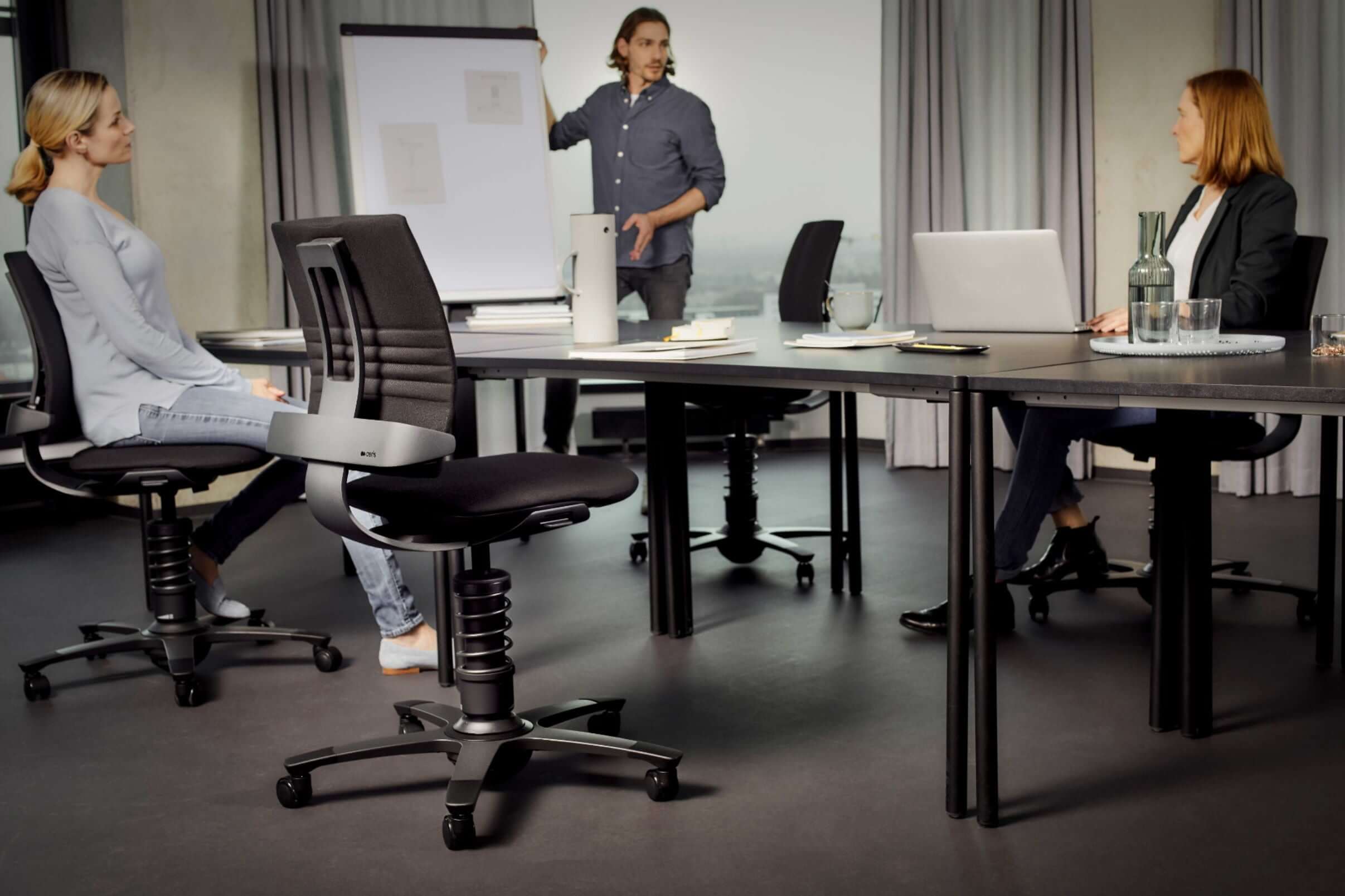 Modern office meeting with professionals using 3Dee active chairs for ergonomic support and movement-friendly seating.