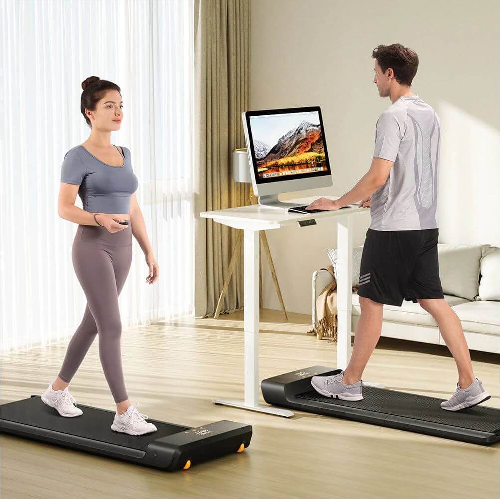 "Man and woman using WalkingPad Pro office treadmills at home, demonstrating compact design and quiet operation for increased activity."