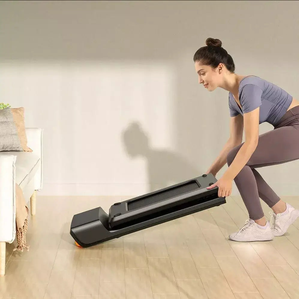 Woman folding compact WalkingPad Pro treadmill in a living room setting.