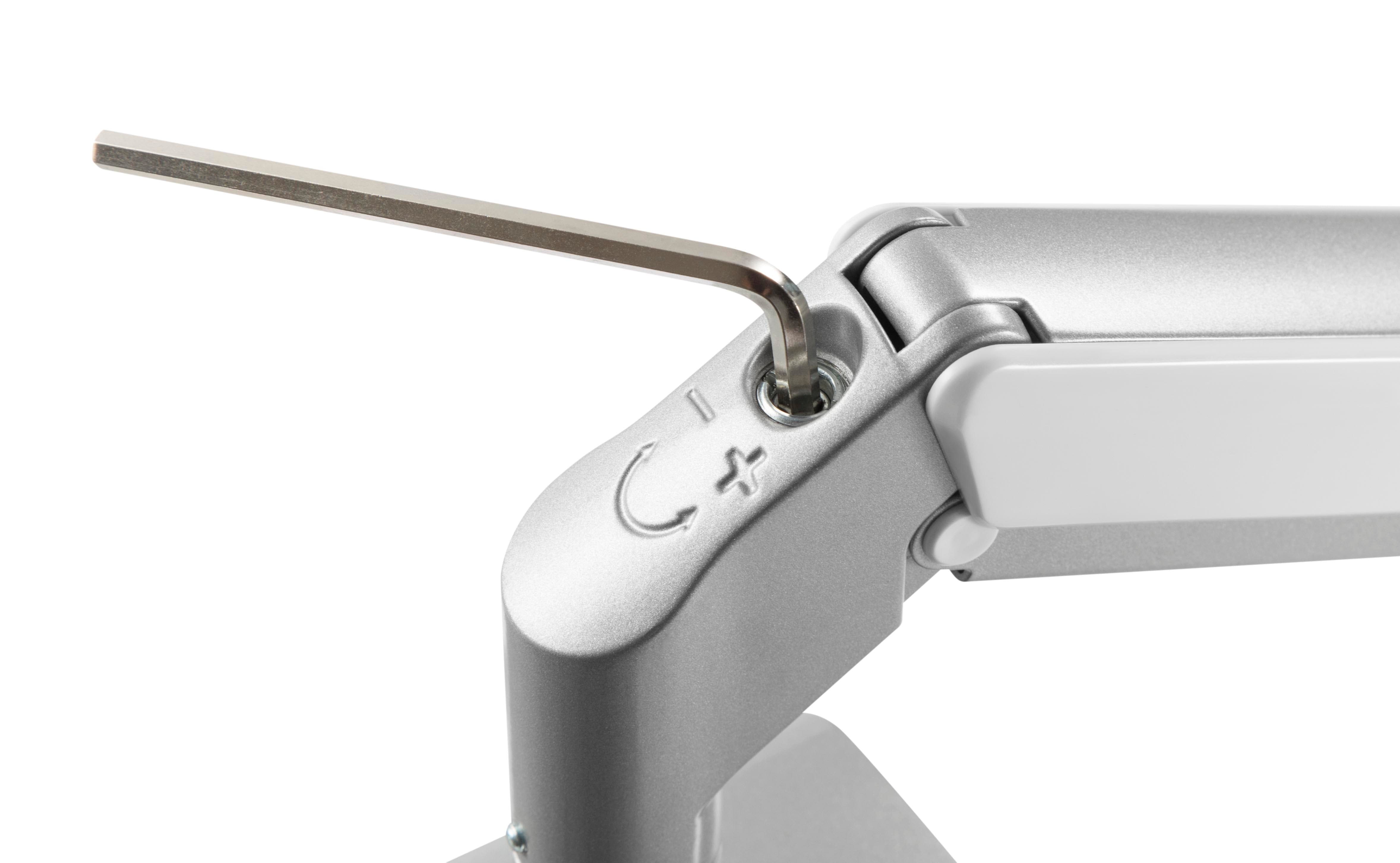 Silver LCD monitor arm with gas spring and adjustment tool visible in hinge.