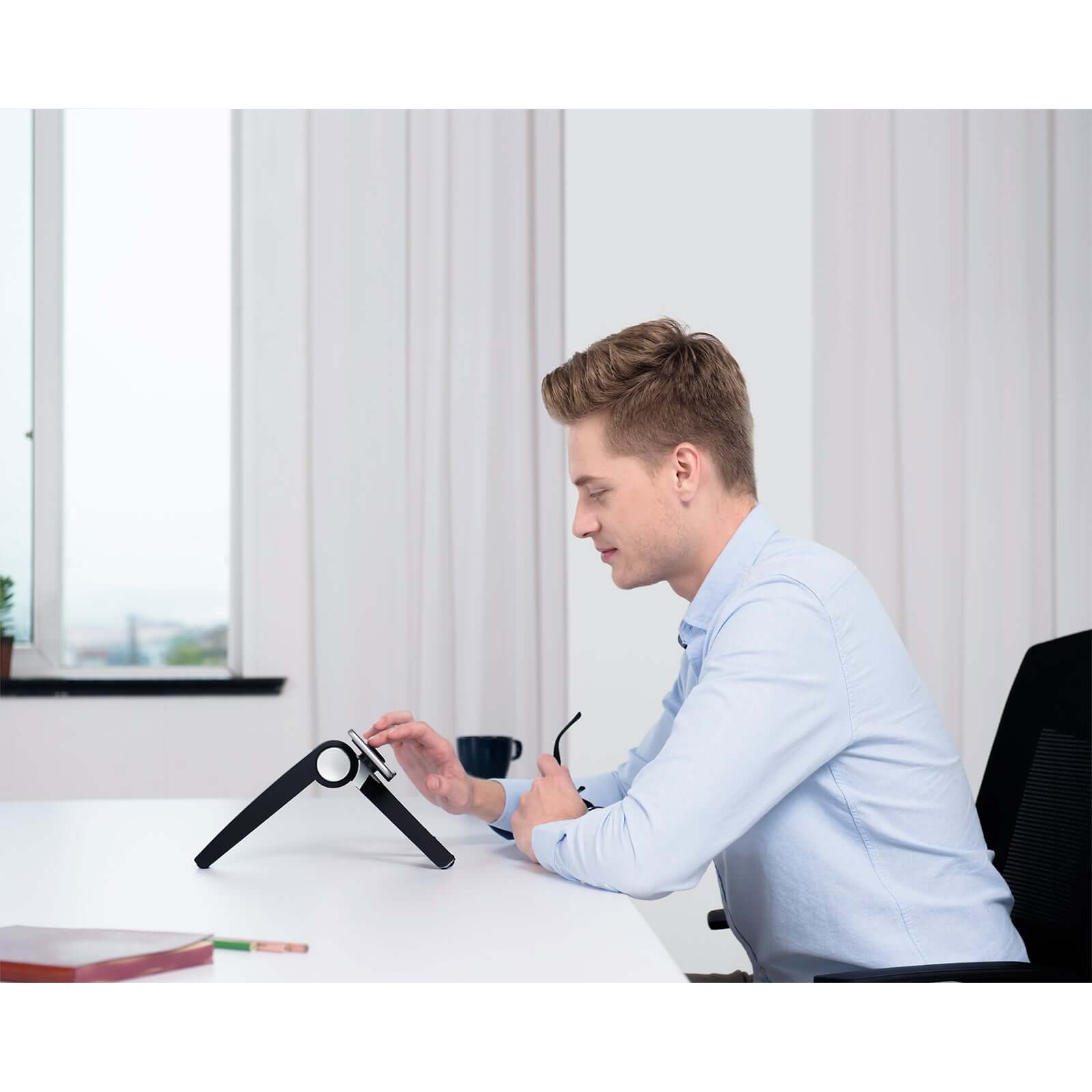 Person using black ErgoFinland Spider laptop and tablet stand on desk in office setting.