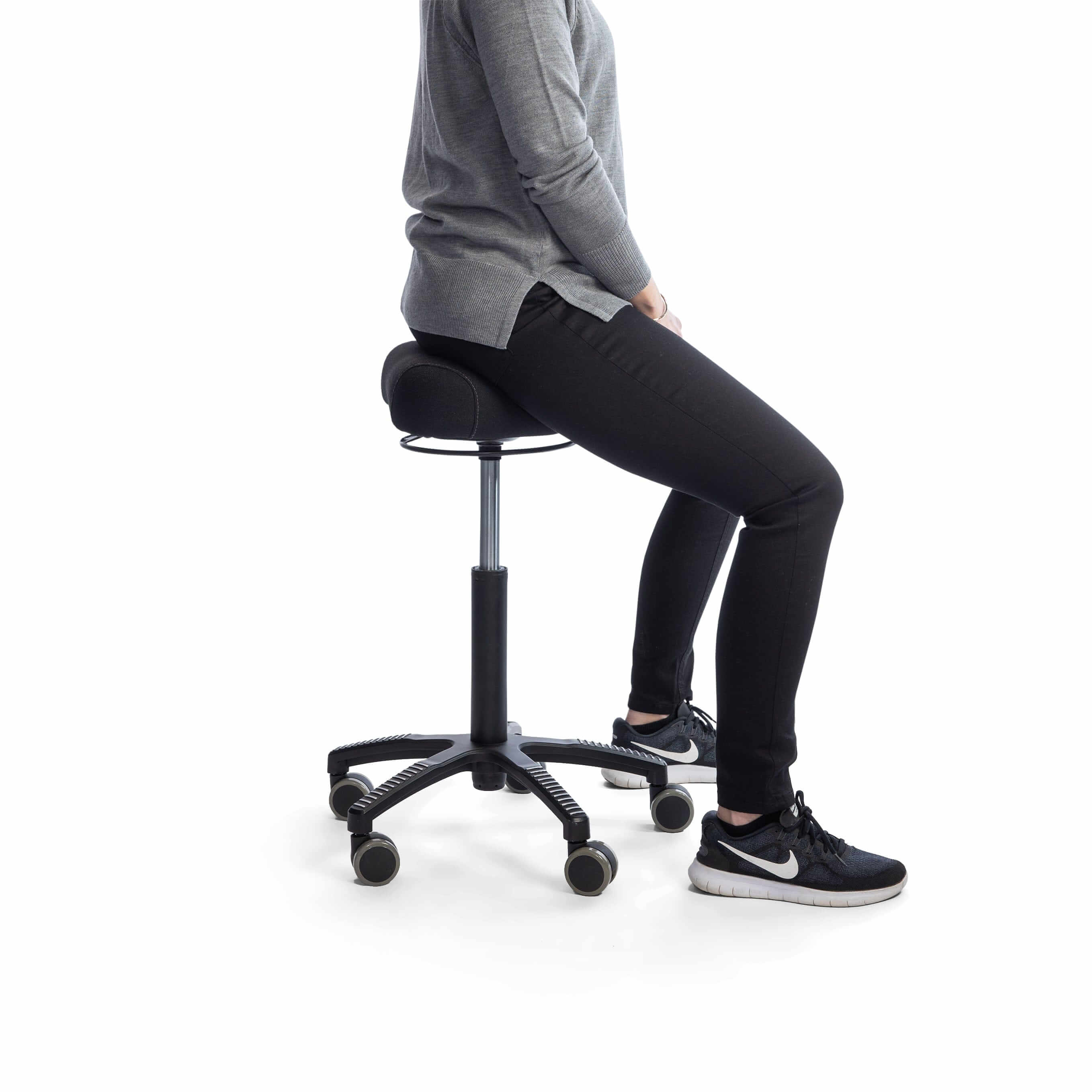 Person sitting on ergonomic swivel chair with wheels and black cushioned seat.