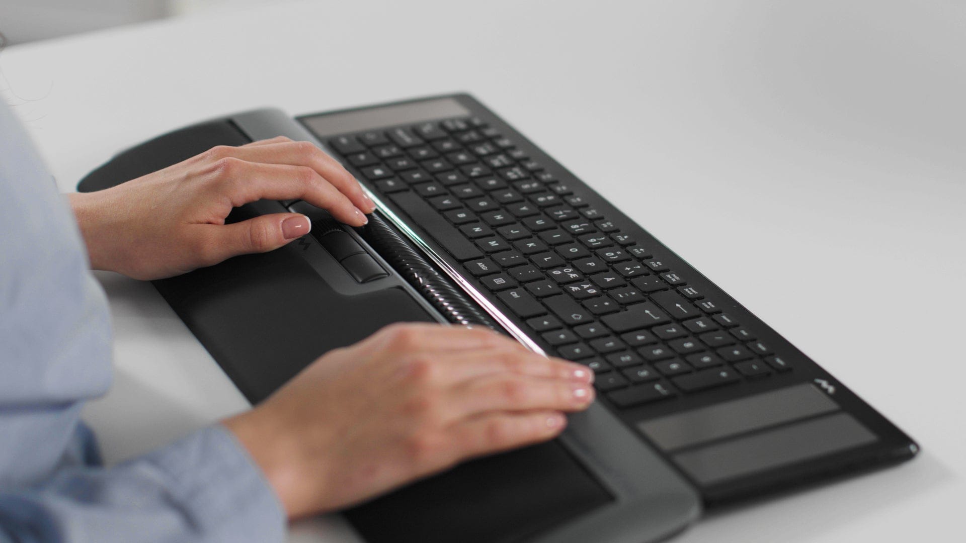 Hands using Mousetrapper Delta Extended keyboard for precision navigation and comfort on a desktop.