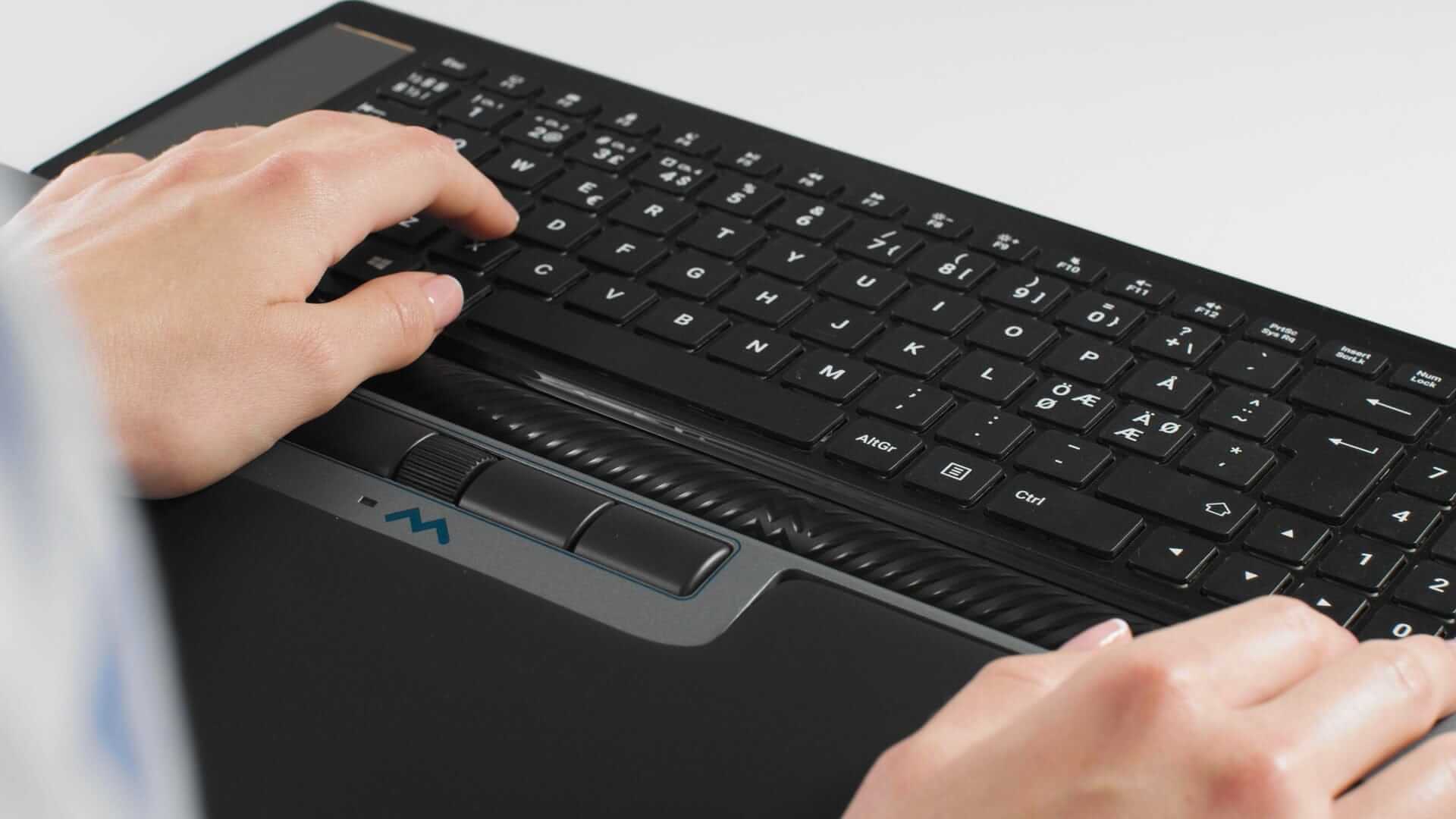 Person typing on Delta Regular black keyboard with 4000 dpi resolution and six programmable buttons, showcasing ergonomic design.