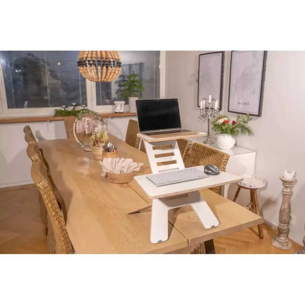 Ergonomic GetUpDesk Light laptop stand additional level enhances workspace comfort on a wooden table in a cozy home office.