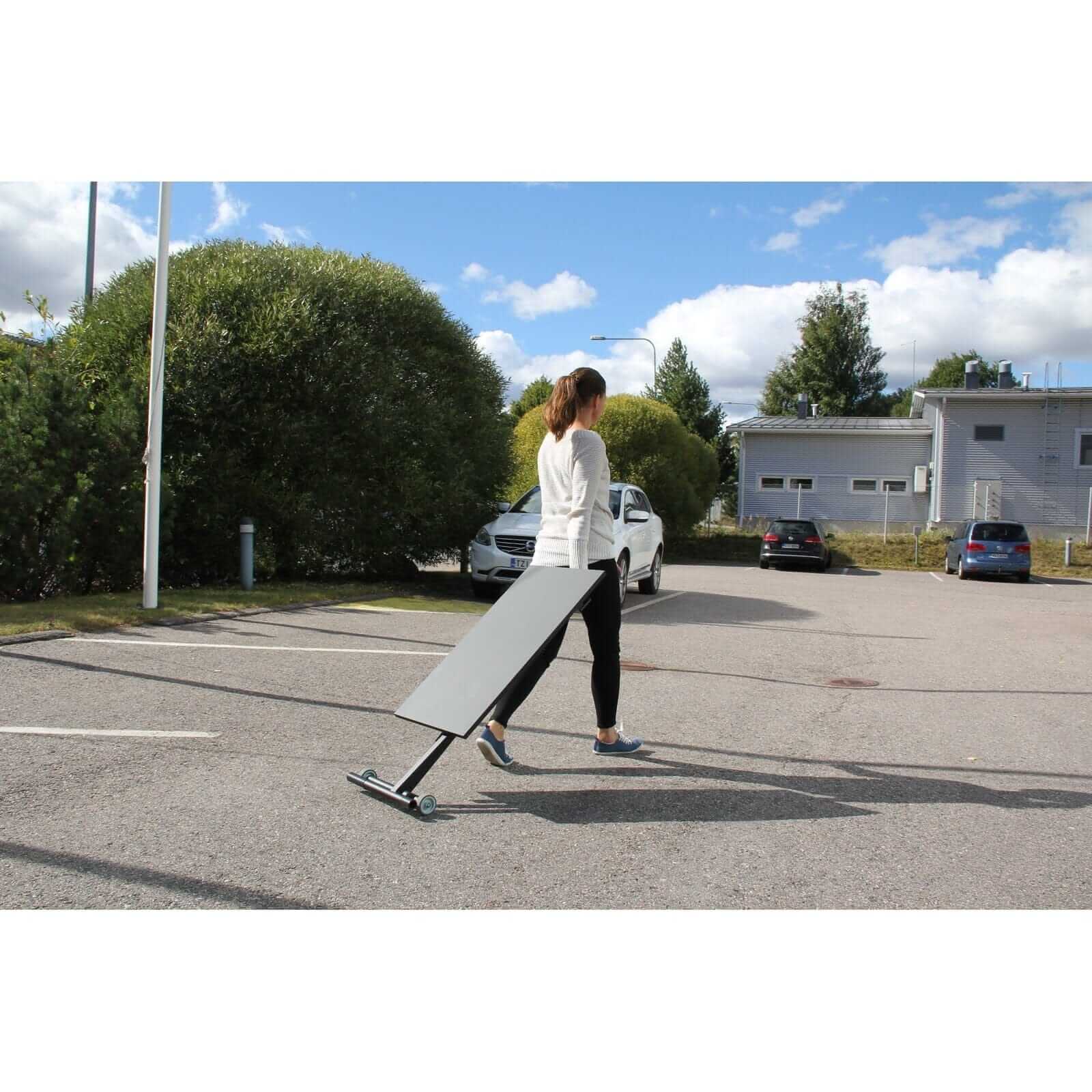 Woman moving a GetUpDesk Move adjustable desk with ease outdoors.