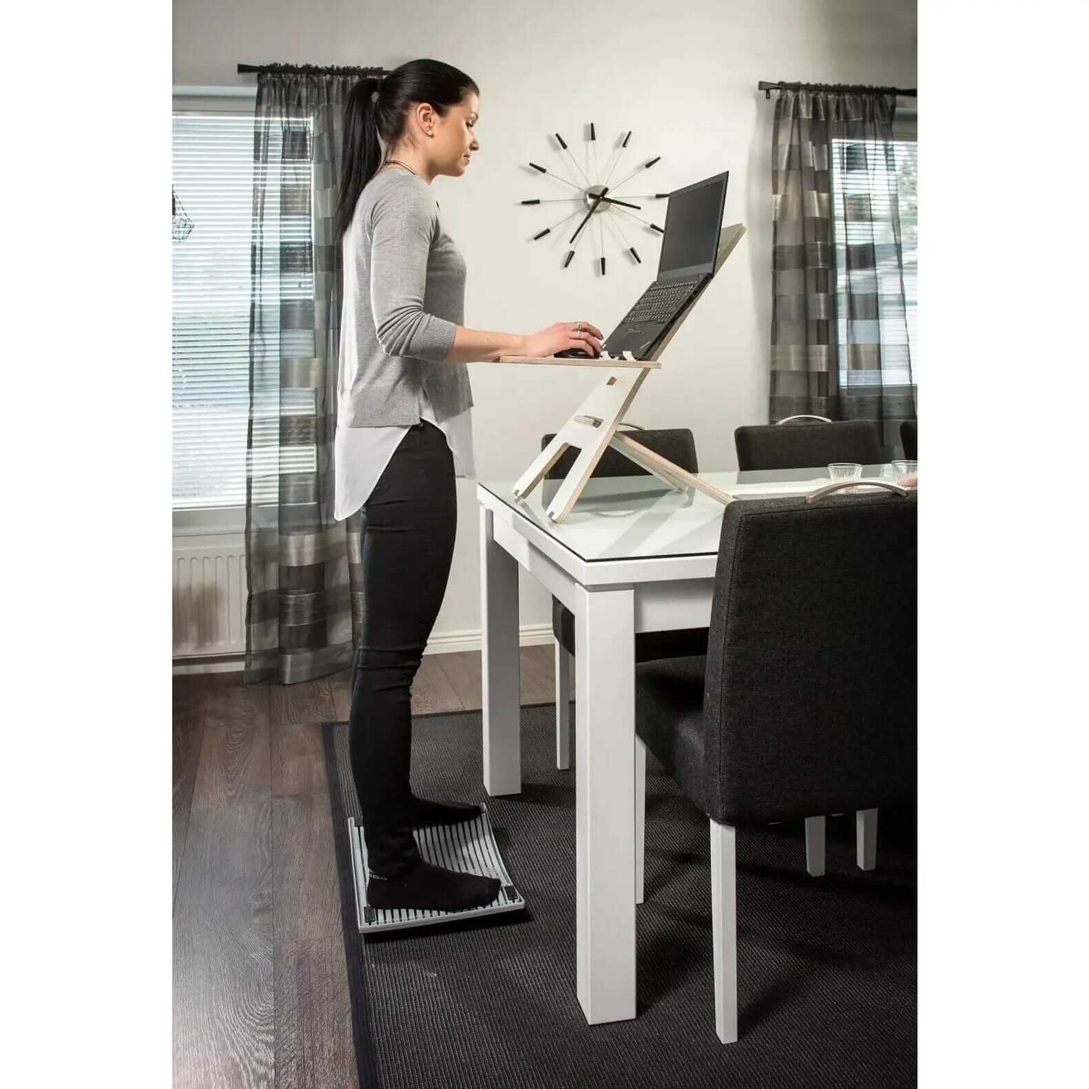 Woman using GetUpDesk light laptop stand rack for ergonomic posture at home office desk.